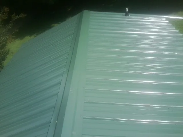 New green metal panels meeting at the ridge of a roof — Flat Roof Repair work by our crew in Wingate