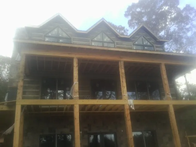 Dormers and porch framing on a large log home under construction — Roof Coating work by our crew in Wingate