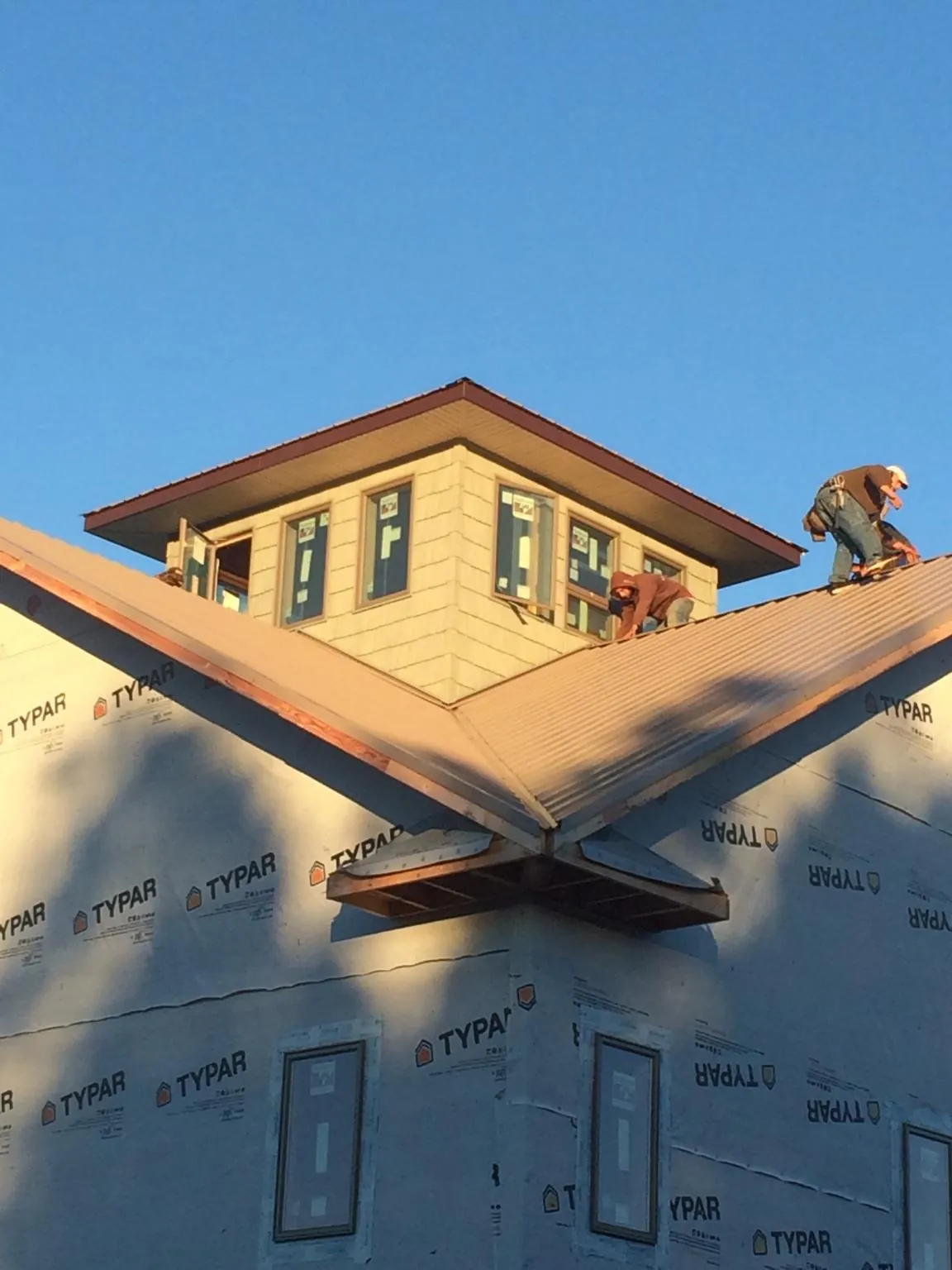 Roofers working around a rooftop cupola on a new metal roof at sunset — Roof Waterproofing in Wingate by Roofing Brothers